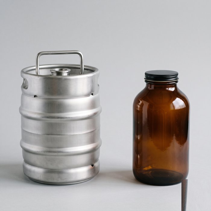 Barril de chope de cinco litros em alumínio ao lado de um growler de vidro