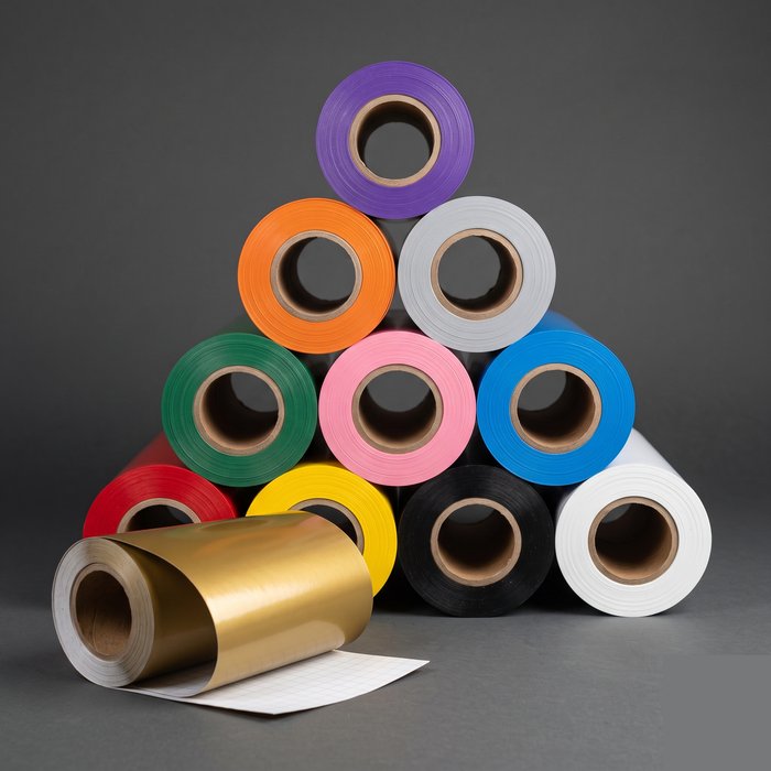 Rolos de vinil adesivo e vinil têxtil de várias cores empilhados